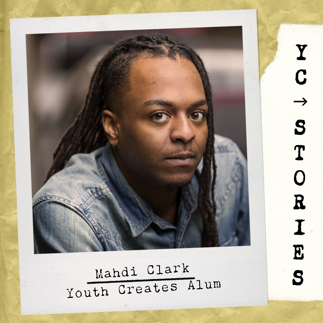 A young black man with dreadlocks is pictured wearing a collared denim shirt.