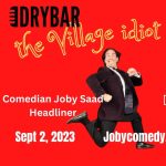 Comedian Joby Saad runs across a red field with the words, The village idiot and friends written in yellow.